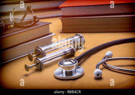 Libri di medicina accanto alle siringhe vintage e stetoscopio, concetto di medicina Foto Stock