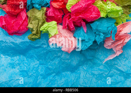Crumpled colorata carta tessuto su un tessuto blu sullo sfondo della carta Foto Stock