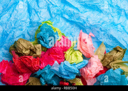 Crumpled colorata carta tessuto su un tessuto blu sullo sfondo della carta Foto Stock