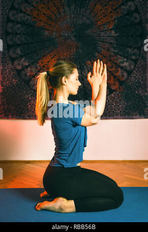 Ritratto di stupendo giovane donna a praticare yoga indoor. Bella ragazza pratica yoga in ambiente tranquillo. Calma e relax, femmina la felicità. Foto Stock