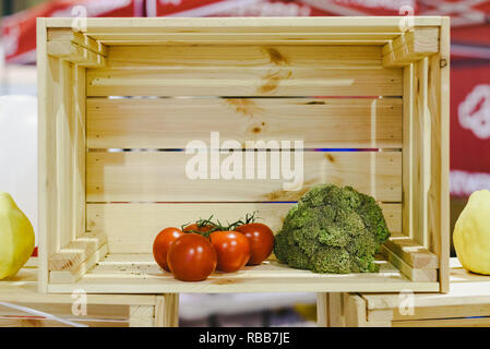 Scatola di legno quasi vuoto, con solo due pomodori e una di broccoli. Foto Stock