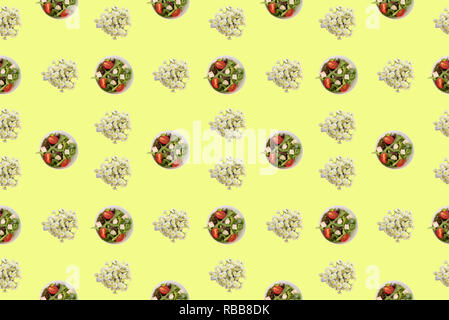 Cup con insalata di verdure e il crisantemo fiori su sfondo giallo. Vista superiore piatta modello di laici Foto Stock