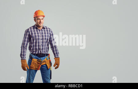 Builder maschio nel casco in un plaid shirt sorridente Foto Stock