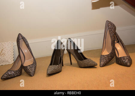 Le spose di scarpe con pattini bridesmaids allineati e in attesa di essere indossato su un giorno di nozze, nero e argento scintillanti scarpe nuziale Foto Stock