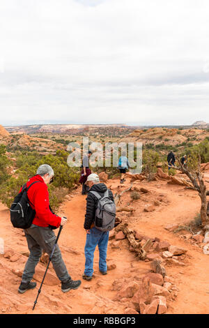 Senior di età compresa tra gli escursionisti a piedi con attenzione il percorso dal Mesa Arch nel Parco Nazionale di Canyonlands. Gli escursionisti più giovani mantenendo un occhio su di essi. Foto Stock