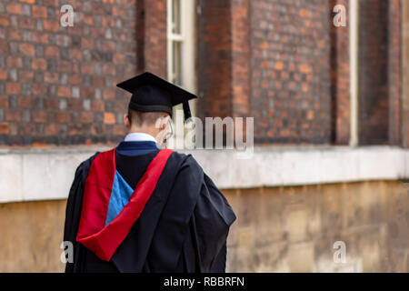 Laureato studente uomo indossa la laurea hat e camice in università camp Foto Stock