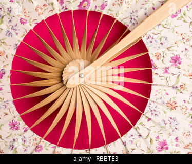 Lay piatto. Tradizionale ventola con la Far Eastern motivo su uno sfondo rosso close up Foto Stock