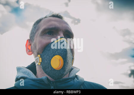Uomo che indossa un vero e proprio anti-inquinamento, anti-smog e virus maschera facciale; smog denso in aria Foto Stock