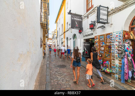 I turisti a piedi per i vicoli del centro storico tra negozi di souvenir e ristoranti tipici, Cordoba, Andalusia, Spagna Foto Stock