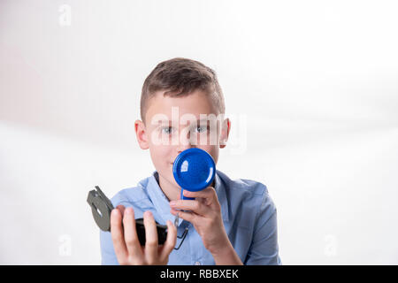 Ragazzo spiega il modo in cui con un megafono blu e una bussola a mano contro un fondo bianco Foto Stock