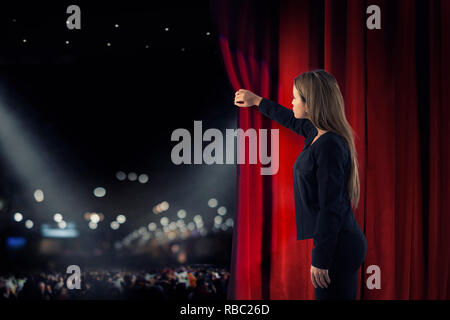 Donna aprire tende rosse del palcoscenico teatrale Foto Stock