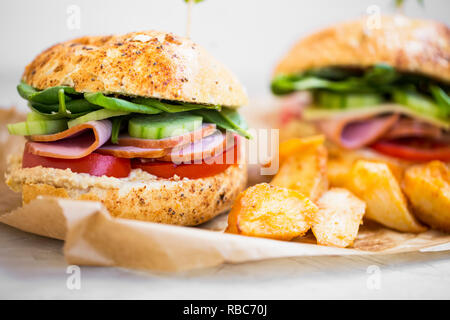 Burger panini al prosciutto , fette di cetriolo, lattuga e pomodori e fette di patate Foto Stock