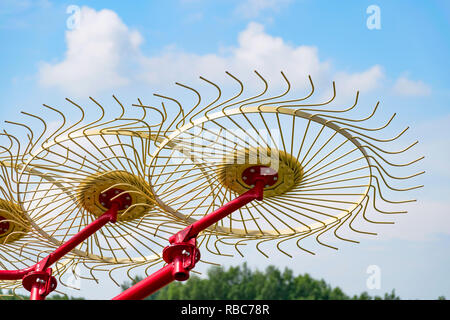 Mandata lato rastrelli o Carted rastrelli ruota sollevata da terra contro il cielo blu. Rastrelli usato per ridurre il tempo di essiccazione e mantenendo i detriti fuori del wi Foto Stock