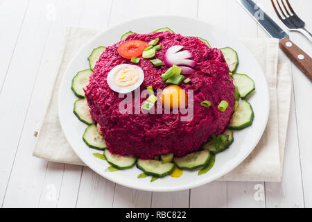 Layered con insalata di aringhe e barbabietole, le carote e le patate e le uova di close-up su una piastra orizzontale. spazio copia Foto Stock