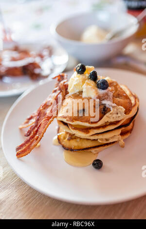 In stile americano a mirtillo frittelle con panna e pancetta e sciroppo d'acero. Foto Stock