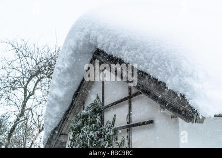 Snow Drift sul tetto dopo due giorni di nevicate. Strati spessi appeso sul tetto di casa. Germania Baviera Foto Stock