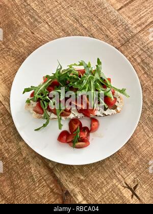 Pasta madre erborinati con formaggio di capra, aceto di pomodori ciliegini e rucola, un snack sani Foto Stock