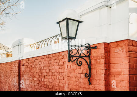 Via lampada su un rosso mattone parete per illuminare le strade del nevoso inverno. Foto Stock