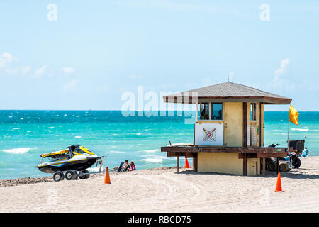 Hollywood, Stati Uniti d'America - 6 Maggio 2018: Lifeguard edificio lungo la costa dell'oceano in Miami Florida durante il giorno con le persone su sabbia e barca Foto Stock