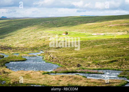 Vista del paesaggio di Islanda prato vicino a Skutustadagigar e Lago Myvatn durante nuvoloso giorno soleggiato e verdi colline di erba con il fiume in estate e casa Foto Stock