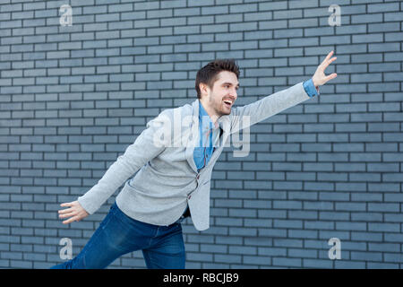 Ciao, è un piacere vedervi. profilo vista laterale ritratto di felice bello uomo barbuto in stile casual in piedi con gesto di saluto e toothy sorridente. indoo Foto Stock