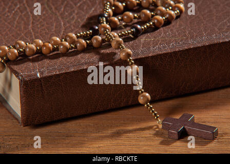 Prenota con rosario sul tavolo di legno. Foto Stock