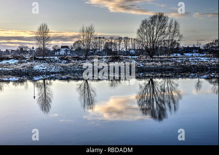 Zutphen, Paesi Bassi, Januari 15, 2017: vista dal centro della città vecchia attraverso lo specchio-come l'acqua del fiume IJssel verso la coperta di neve ru Foto Stock