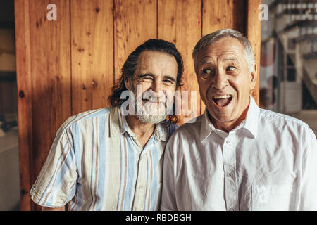 Due pazzi senior amici assieme facendo facce buffe. Pensionati uomini divertendosi insieme a casa. Foto Stock