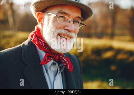 Elegante uomo vecchio in un soleggiato parco di autunno Foto Stock