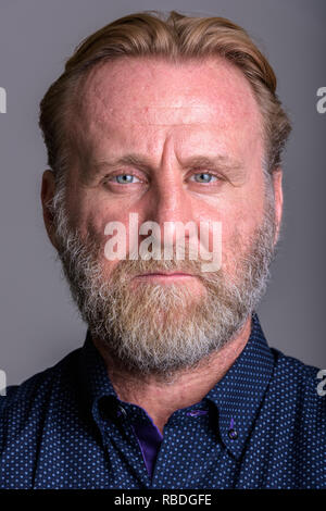 Faccia di maturo uomo barbuto in uno sfondo grigio Foto Stock