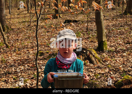 Geocaching boy trova una ben mimetizzata cache nella foresta Foto Stock