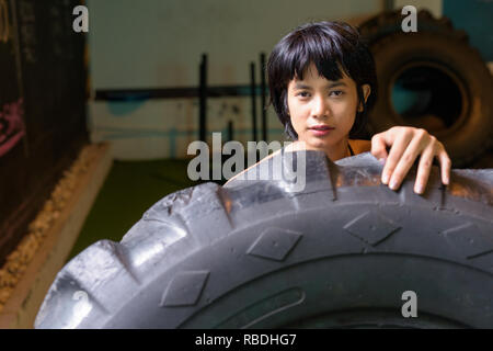 Asia donna fitness di spinta e di ribaltamento ruota carrello pneumatico in palestra Foto Stock