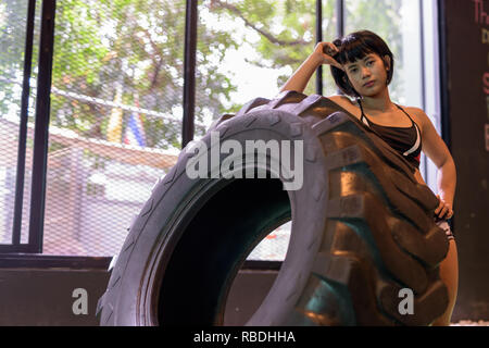 Asia donna fitness di spinta e di ribaltamento ruota carrello pneumatico in palestra Foto Stock