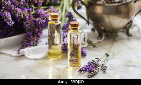 Olio di lavanda bottiglie, erba naturale consept cosmetici con fiori di lavanda flatlay su sfondo di pietra Foto Stock