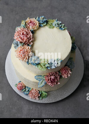 Grande torta di nozze, decorato con fiori di crema di burro, sulla pietra grigia sullo sfondo Foto Stock