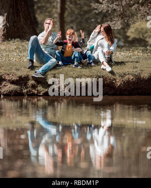 Genitori e figli dando a ogni altro un alto cinque su una passeggiata nel parco Foto Stock