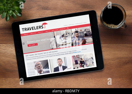 Il sito web di viaggiatori business assicurativo è visto su un tablet iPad, appoggiato su un tavolo di legno (solo uso editoriale). Foto Stock