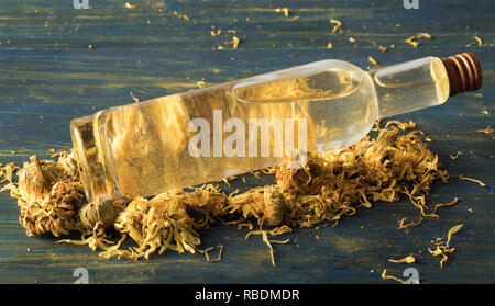 Viso tonico di calendula e camomilla e golden mica, su uno sfondo di legno Foto Stock