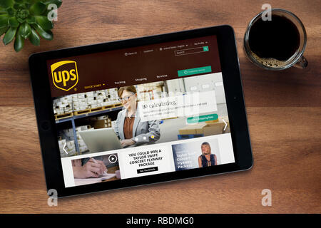 Il sito web di UPS (United Parcel Service) è visto su un tablet iPad, appoggiato su un tavolo di legno (solo uso editoriale). Foto Stock