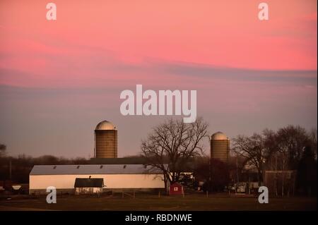 South Elgin, Illinois, Stati Uniti d'America. La luce dal sole al tramonto si riflette nelle nuvole al di sopra di un moderno caseificio. Foto Stock