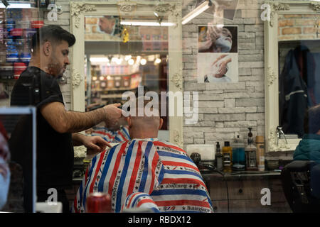 Parrucchiere che rifinisce un taglio di capelli mans con un trimmer elettrico presso il salone di Leeds Market, West Yorkshire, Inghilterra, UK. Foto Stock