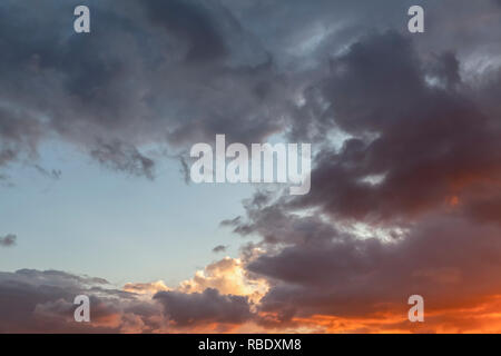 Drammatica cloudscape skies con fiery rosso e grigio scuro nuvole. Alcuni blue sky ahowing attraverso le nuvole Foto Stock