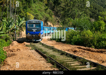 Lunga distanza commuter train voce fuori di Ella, Sri Lanka passando attraverso un taglio. Foto Stock