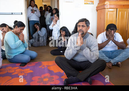 Dopo servizi & prima di alimentare i monaci, adoratori sedersi e pregare e meditare. In un tempio buddista in Queens Village, New York City. Foto Stock