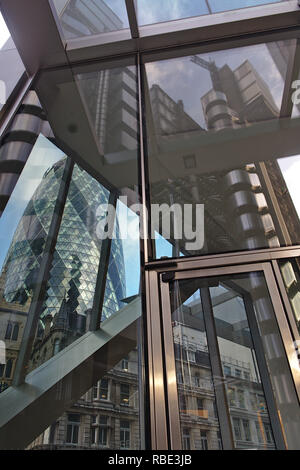 La riflessione di Lloyd's edificio in vetro del bisturi con il Gherkin mostra attraverso l'altro lato. Foto Stock