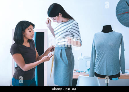 Tutto ciò per i clienti. Nice professional sarta rendere più corto del vestito di prendere misure a partire dal suo cliente Foto Stock