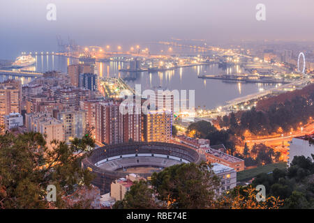 Città spagnola di Malaga per notte. Il porto e la città vecchia con una bull ring dal di sopra alla luce artificiale. Edifici e navi in porto può essere vedere Foto Stock