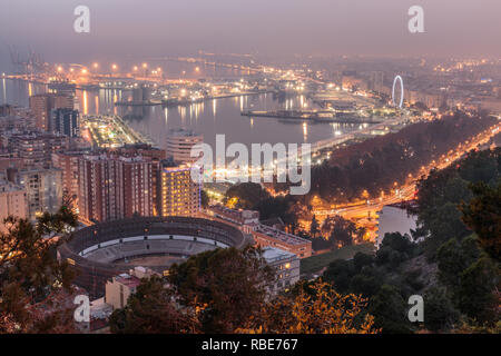 Città spagnola di Malaga per notte. Il porto e la città vecchia con una bull ring dal di sopra alla luce artificiale. Edifici e navi in porto può essere vedere Foto Stock