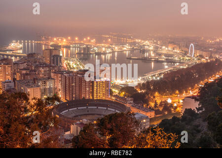 Città spagnola di Malaga per notte. Il porto e la città vecchia con una bull ring dal di sopra alla luce artificiale. Edifici e navi in porto può essere vedere Foto Stock