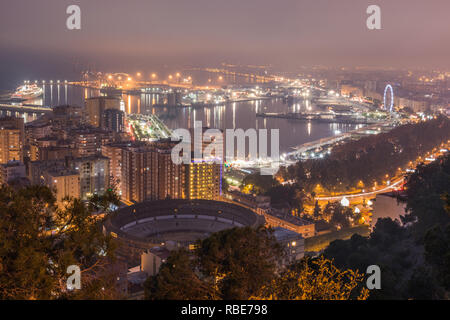 Città spagnola di Malaga per notte. Il porto e la città vecchia con una bull ring dal di sopra alla luce artificiale. Edifici e navi in porto può essere vedere Foto Stock